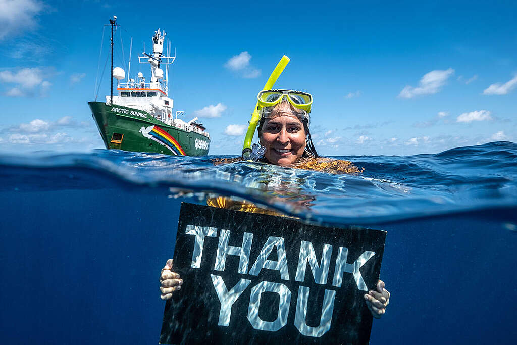 Campaigner Juliana Costa in the Indian Ocean, 2021, holding a sign thanking our supporters.