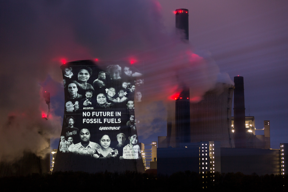 Projection on a condensing tower at a coal-fired power station depicting the people affected by climate change and the caption “No Future in Fossil Fuels”