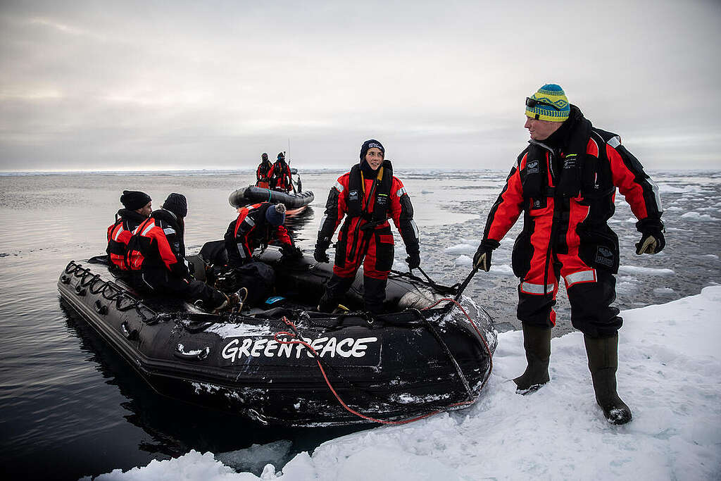 Polar guide Tom Foreman holds a RHIB steady as people disembark onto an ice floe in the Arctic. A Greenpeace team is in the Arctic to document the impact of the climate crisis and investigate marine life in the region.
