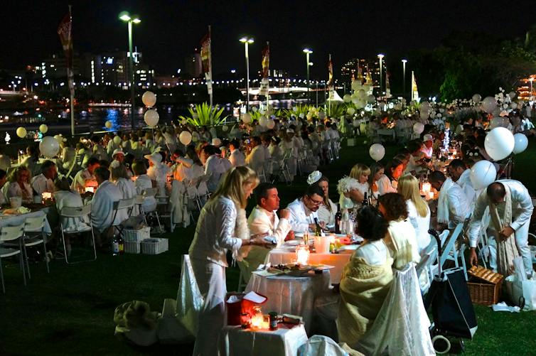 People eating dinner at long tables dressed in white