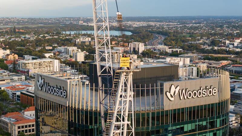 Greenpeace activists drop a 25m 'Stop Woodside' banner from a crane outside Woodside's headquarters in Perth, WA