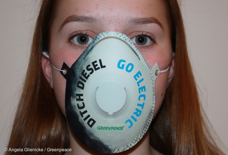 Teenage girl wearing air pollution mask saying ' ditch diesel, go electric'.