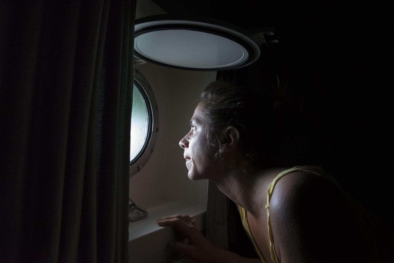 Rainbow Warrior III cook Laurence Nicoud wakes and checks the weather from her cabin.