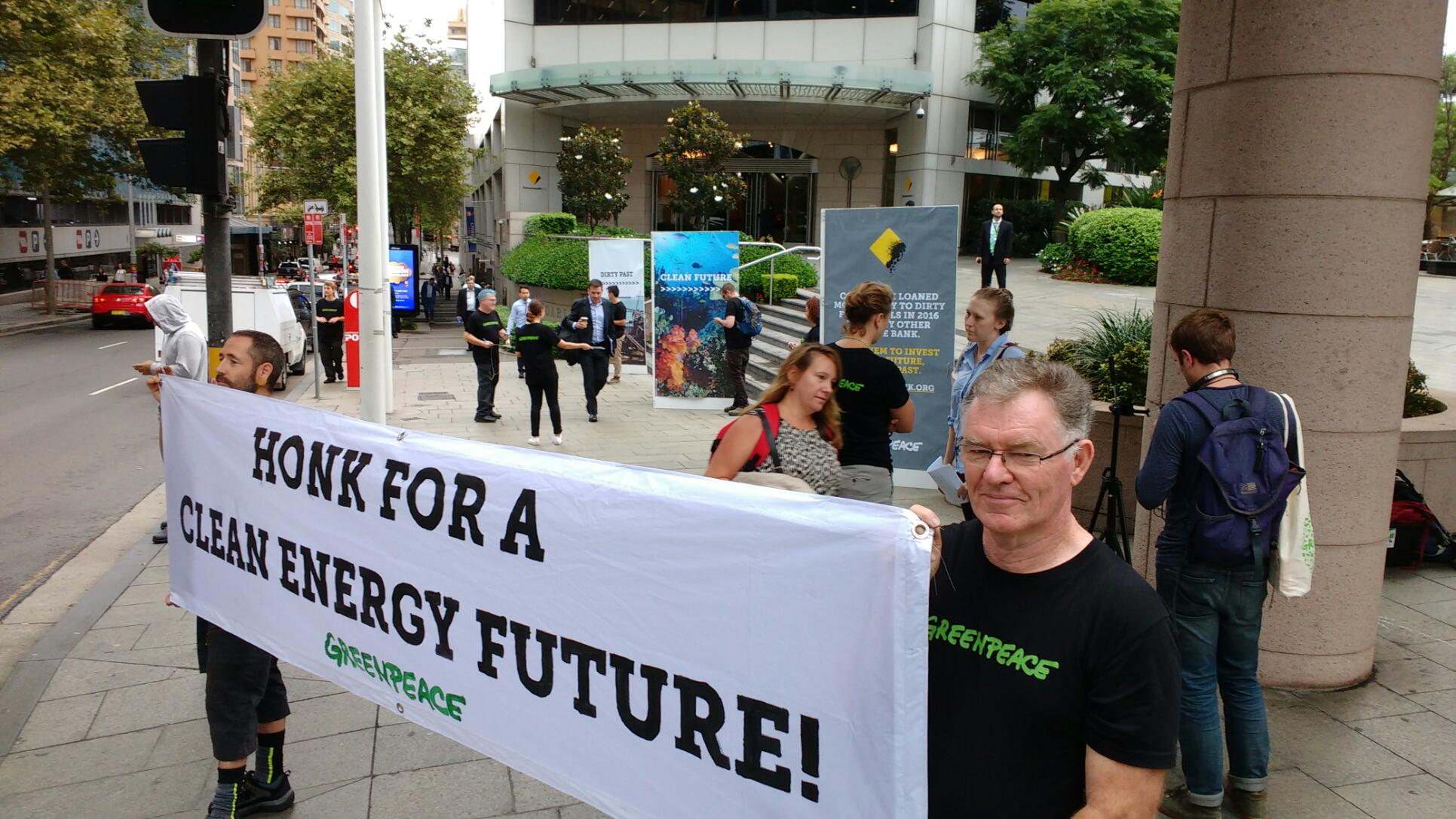 Volunteers outside CommBank HQ hold a sign saying 'Honk for a clean energy future!'