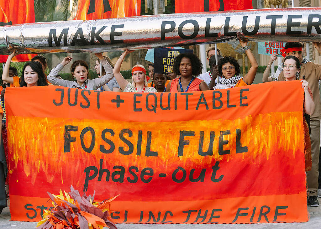 Activists hold banners to make polluters pay, calling for a just and equitable fossil fuel phase out.