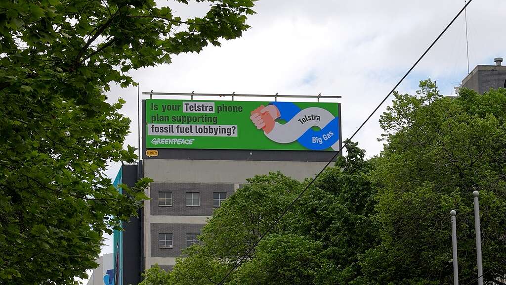 A Greenpeace billboard right in view of Telstra's headquarters in Melbourne, posing the question is your phone plan supporting fossil fuel lobbying?