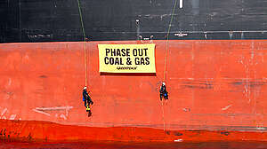 Greenpeace activists hang phase out fossil fuels banner from a coal ship at the Rising Tide protestival in Newcastle