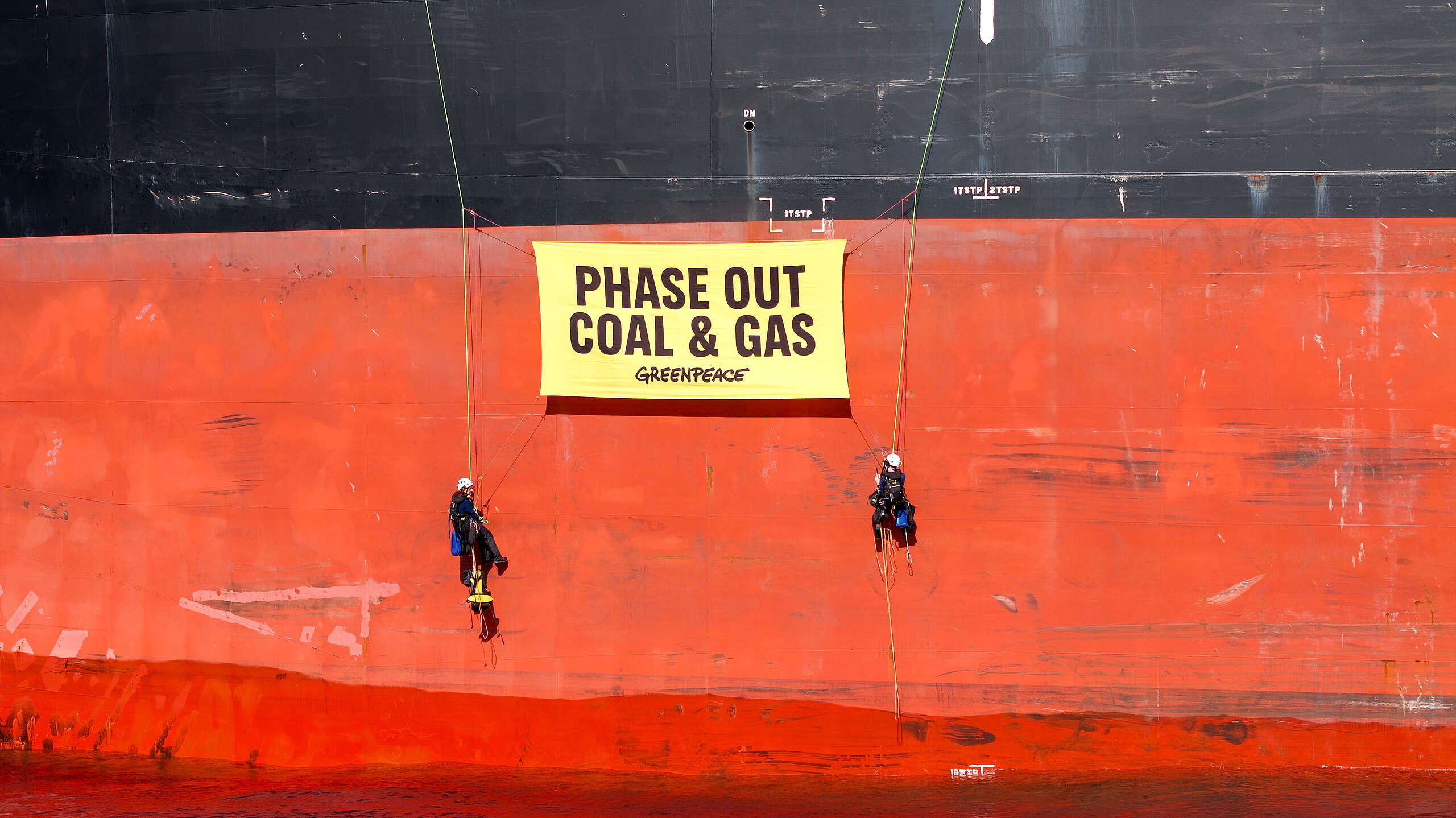 Greenpeace activists hang phase out fossil fuels banner from a coal ship at the Rising Tide protestival in Newcastle