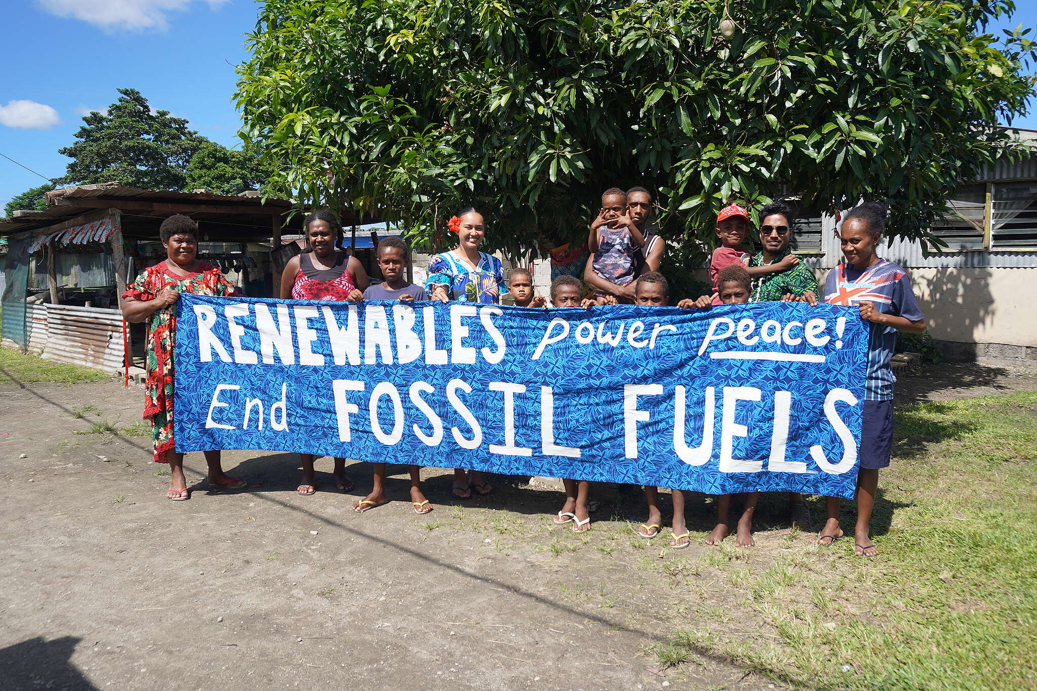 The community in Mele, Vanuatu hold a banner saying 'Renewables power peace! End fossil fuels' ahead of the first conference on transitioning away from fossil fuels