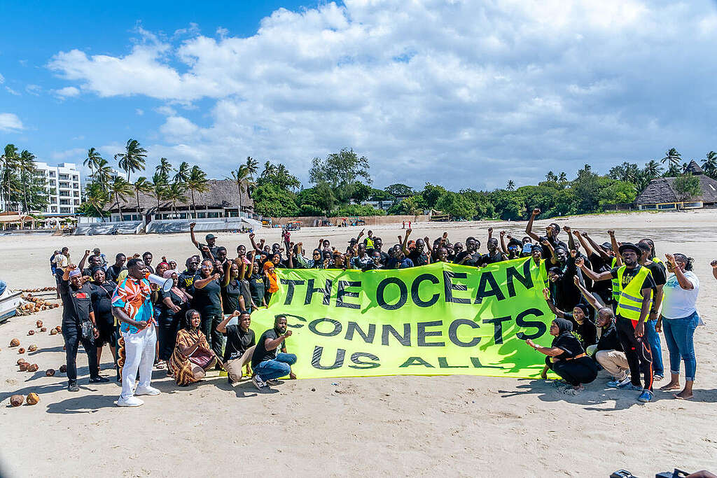 Volunteers and community members hold a banner reading, "The ocean connects us all" at Pirates Beach/ Jomo Kenyatta Beach in Mombasa, Kenya.