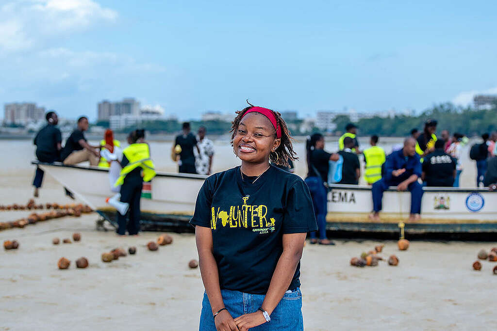 A community member at Pirates Beach/ Jomo Kenyatta Beach in Mombasa, Kenya around a sand installation carrying the message "The Ocean Connects Us All".